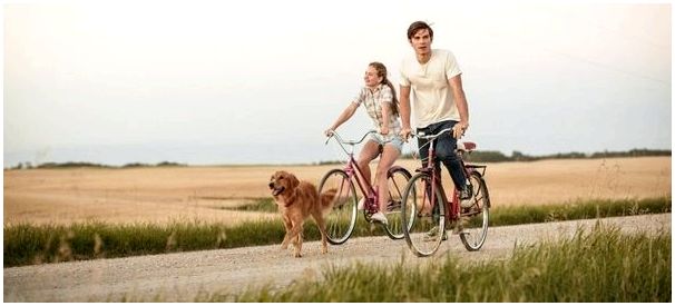Взрослый Итан катается на велосипеде с девушкой и Бэйли